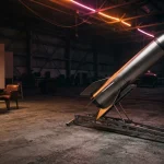 A sleek model rocket in a dark hangar, warm neon lighting on its metal surface and a gaming table beyond
