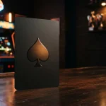 A dramatic black playing card with a sculpted spade symbol beside a softly glowing casino arcade cabinet