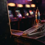 A miniature rocket on a lit launch rail in a dark arcade, with a glowing gaming cabinet in the background