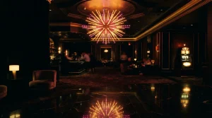 Glowing starburst chandelier over a dark casino lounge with a softly lit slot machine in the background