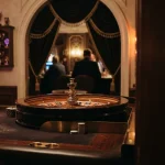 An elegant European-style roulette wheel beside a dark velvet gaming lounge illuminated with playful amber neon