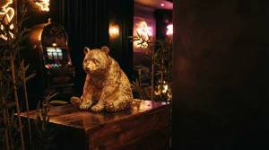 A realistic golden panda sculpture among bamboo in a dark neon-lit lounge, with a vintage slot machine behind it