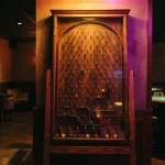 A physical Plinko board glowing in a dark neon lounge, with a softly lit casino table in the background