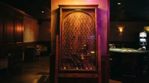 A physical Plinko board glowing in a dark neon lounge, with a softly lit casino table in the background