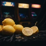 Fresh lemons piled beside a glowing vintage arcade cabinet in a dark lounge with warm neon lighting