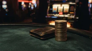 Stacks of unmarked metallic crypto tokens on a dark gaming table, with a softly glowing slot machine behind them