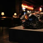 An illuminated obsidian rock displayed in a dark neon arcade lounge, with softly glowing gaming machines behind it