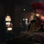 Weathered bronze Spartan helmet on a dark stone plinth with a softly glowing arcade machine in the background